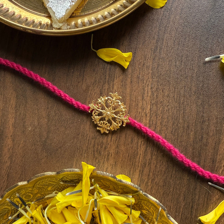 Sweets on a gold plate with yellow flowers and a pink thread on a wooden surface