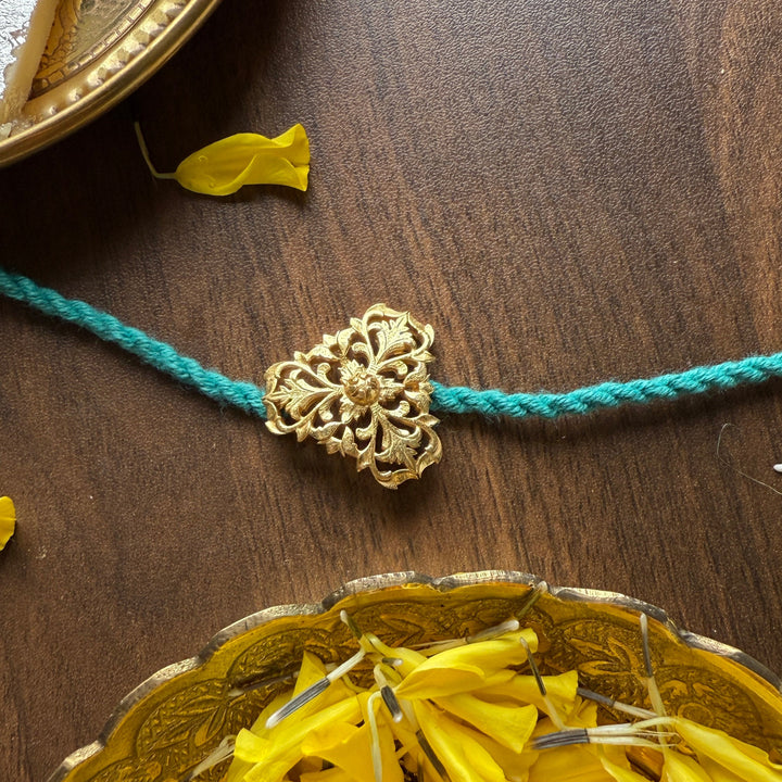Gold bracelet with decorative clasp on a wooden surface with yellow flowers and a pumpkin.